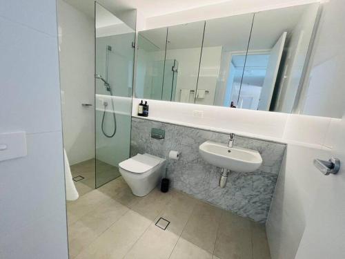 a bathroom with a sink and a toilet and a mirror at Stylish Chatswood 2BR Apartment with 3 Beds, Gym, Near Metro in Sydney