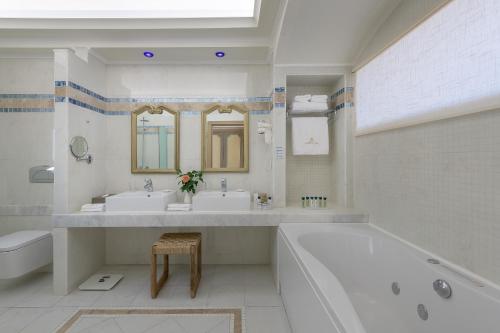 a bathroom with two sinks and a tub and a toilet at Atrium Prestige Thalasso Spa Resort & Villas in Lachania