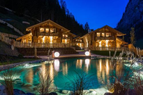 a log home with a pond at night at Chaletdorf Auszeit in Hüttschlag