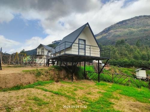 a house with a roof on top of a field at Hazy Mount Vattavada in Kottakamboor