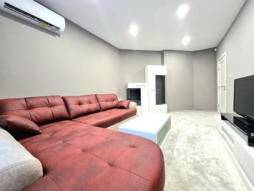 a living room with a brown leather couch and a television at Alexandrovska - Super Centar Luxury Apartment in Burgas City