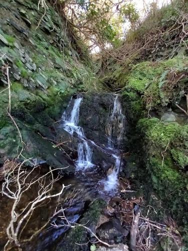 a small waterfall on the side of a hill at Gleann Loic Farmhouse in Dingle