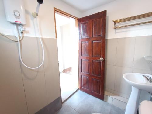 a bathroom with a shower and a wooden door at Shoreline Guesthouse 海岸线客栈 in Semporna