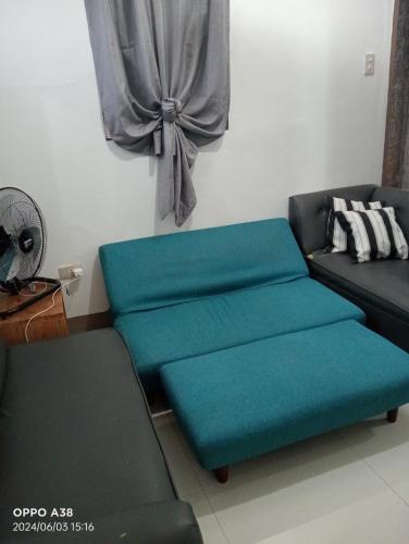 a living room with a couch and a blue ottoman at RY Nest main in Malaybalay