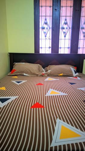 a bed with colorful comforter with stained glass windows at Sri BALAJI homestay Guest house in Tiruvannāmalai