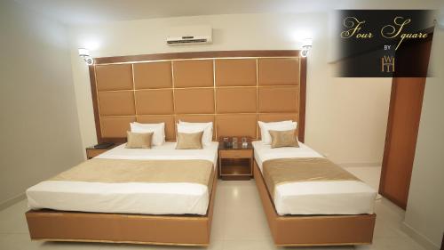two beds in a hotel room with two bedsskirtspectspectspectssenalsenalsenal at Four Squares by WI Hotel in Karachi