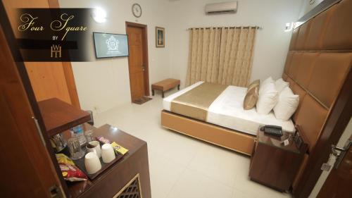 a small bedroom with a bed and a tv at Four Squares by WI Hotel in Karachi