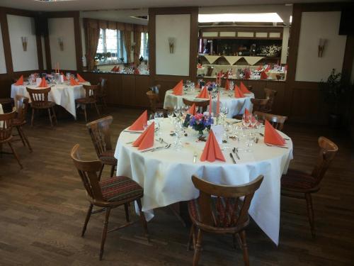 a dining room with white tables with orange napkins at Hotellerie Gasthaus Schubert in Garbsen
