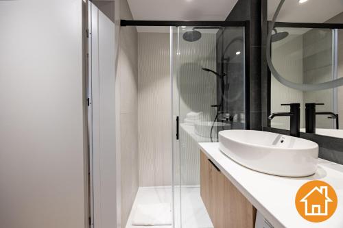 a white bathroom with a sink and a shower at Apartamenty Baltic Waves - visitopl in Międzyzdroje