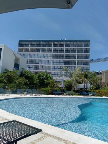 a swimming pool in front of a large building at Hermoso Depto en Condominio Astoria in Acapulco
