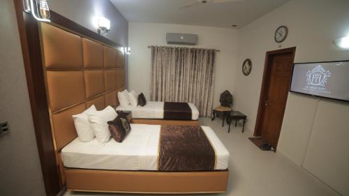 two beds in a hotel room with a television at Four Squares by WI Hotel in Karachi