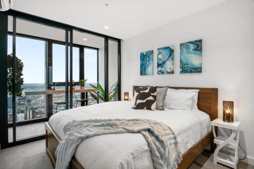 a bedroom with a large bed and large windows at Gorgeous City Views 71st Floor 3BR Apartment with Pool and Gym in Melbourne