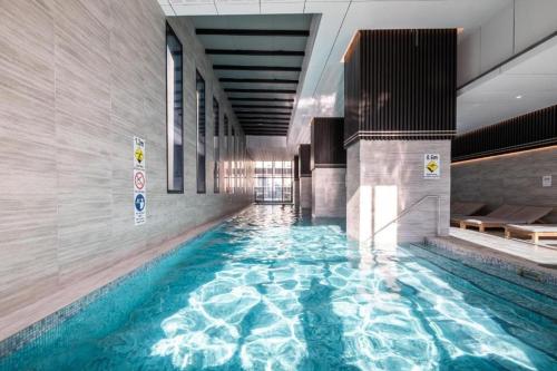a large swimming pool in a building with blue water at Gorgeous City Views 71st Floor 3BR Apartment with Pool and Gym in Melbourne