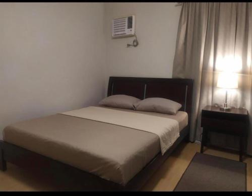 a bedroom with a bed and a lamp and a window at Mactan Guesthouse in Cogon