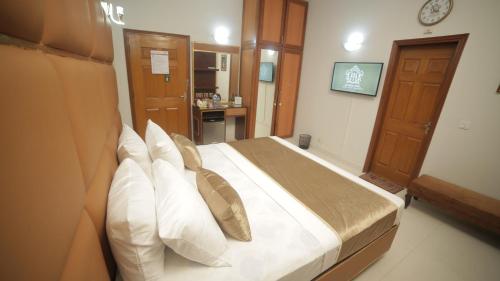 a bedroom with a large bed with white pillows at Four Squares by WI Hotel in Karachi