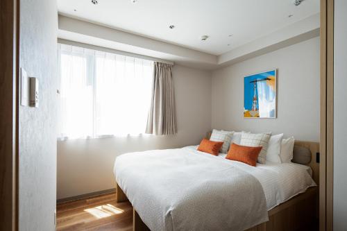 a bedroom with a large white bed with orange pillows at Section L Shimbashi West in Tokyo