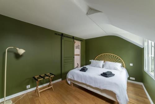 - une chambre avec des murs verts et un lit avec des draps blancs dans l'établissement Le Muguet - Central - Proche plage, à Villerville