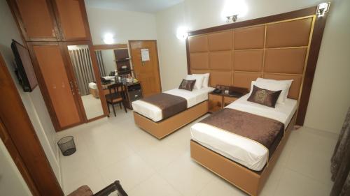 a hotel room with two beds and a desk at Four Squares by WI Hotel in Karachi