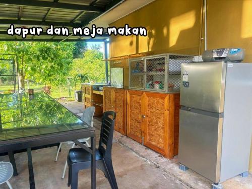 a kitchen with a table and a refrigerator at Dangau Tokwan in Pokok Sena