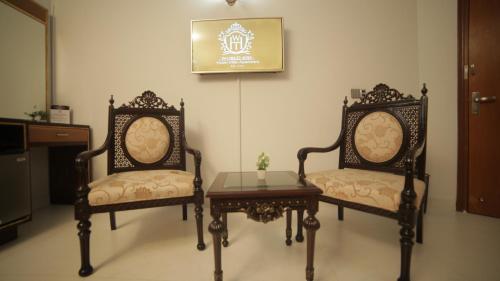 two chairs and a table in a room at Four Squares by WI Hotel in Karachi