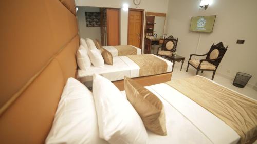 a hotel room with three beds with white pillows at Four Squares by WI Hotel in Karachi