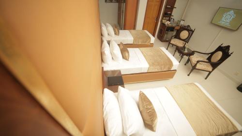 a room with three beds with white sheets and pillows at Four Squares by WI Hotel in Karachi