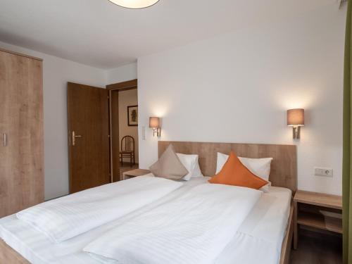 a bedroom with a large white bed with orange pillows at Appartements Pungg in Fügen