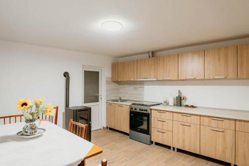 Una cocina con gabinetes de madera y una mesa con un jarrón de flores. en Vi La June, en Chimindia