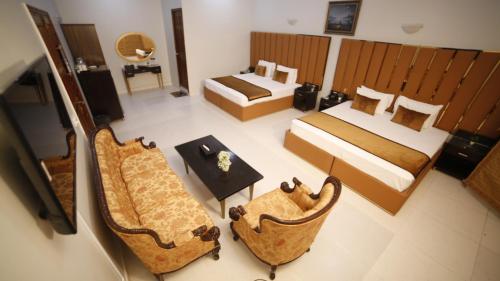 a hotel room with two beds and a table and chairs at Four Squares by WI Hotel in Karachi