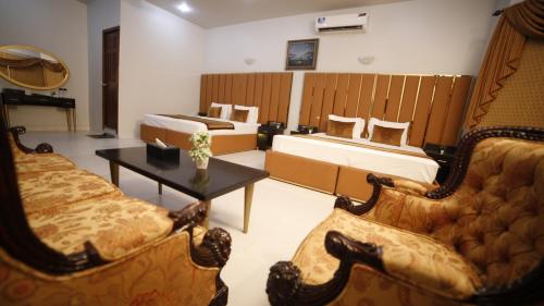 a room with two beds and a couch and a table at Four Squares by WI Hotel in Karachi