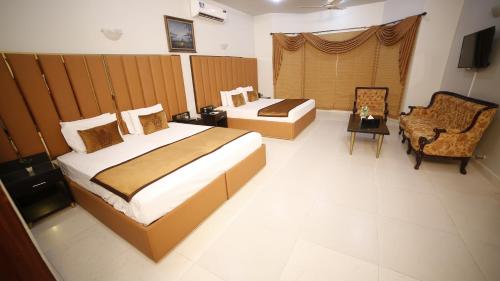 a hotel room with two beds and a chair at Four Squares by WI Hotel in Karachi