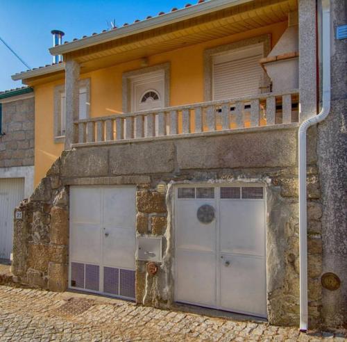 a building with two garage doors and a balcony at Refúgio do Canas in Rapoula do Côa