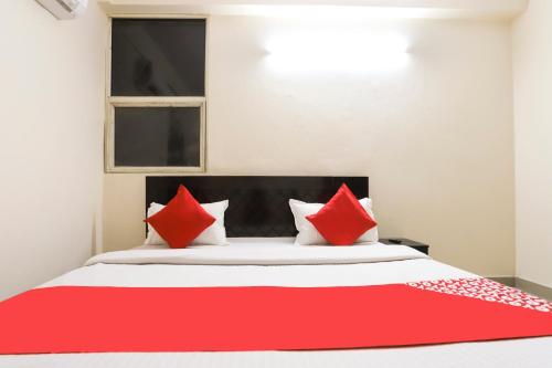 a red and white bed with red pillows on it at Hotel O Royal Residenc in Indirapuram