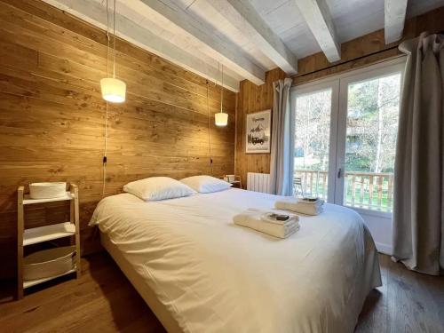 - une chambre avec un lit blanc et un mur en bois dans l'établissement Chalet charmant à Saint-Lary-Soulan avec cheminée, à Saint-Lary-Soulan