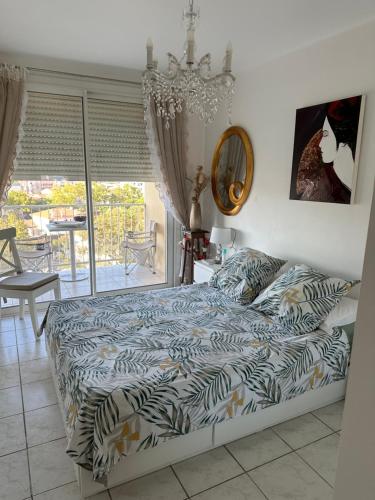 une chambre avec un lit et un lustre dans l'établissement Charmant Appartement de 42 m à 200 m de la Plage, à Fréjus