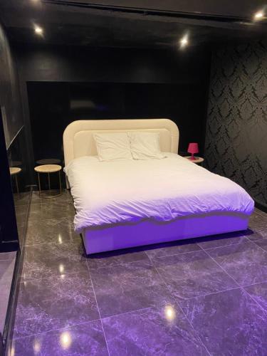 łóżko w pokoju z fioletową podłogą w obiekcie La Suite Marylin, Loft de 90m2 avec Sauna et Jacuzzi w mieście Riom