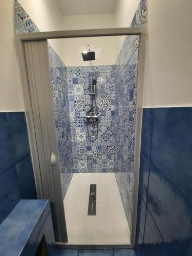 a bathroom with a shower with blue and white tiles at Sul Mare Apartment in Capo dʼOrlando