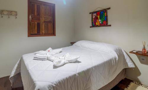 a bedroom with a white bed with towels on it at Guest House 4 Anjinhos in Arraial d'Ajuda
