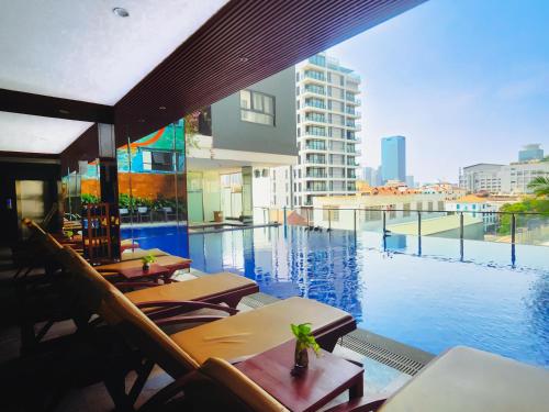 a swimming pool with tables and chairs next to a building at Poulo Wai Hotel & Apartment in Phnom Penh