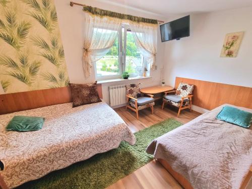 a room with two beds and a table and a window at Kacperek w centrum Willowa 4A in Szczyrk