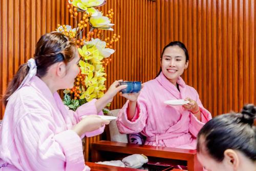 a woman in pink holding a cup and plate of food at Poulo Wai Hotel & Apartment in Phnom Penh