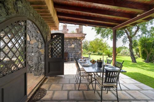a patio with a table and chairs and a stone wall at Saracina in Aci Catena