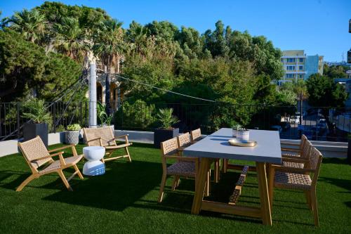 a table and chairs on a lawn with trees at Monarco Executive Rooms in Rhodes Town