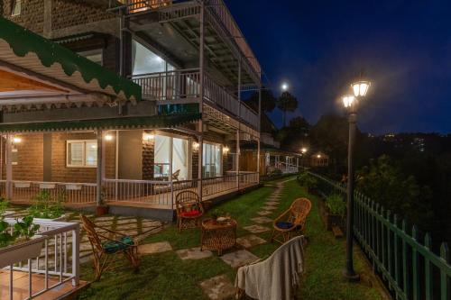 a house with chairs and a patio at night at ELIVAAS 3 BHK with Garden & Scenic Views - Alpenglow in Kasauli
