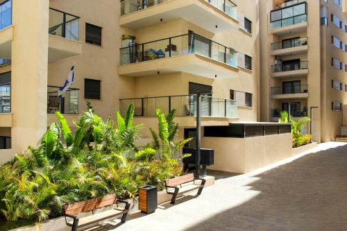 a apartment building with two benches in front of it at Luxury Family Apartment #28 By Hashdera Eilat in Eilat