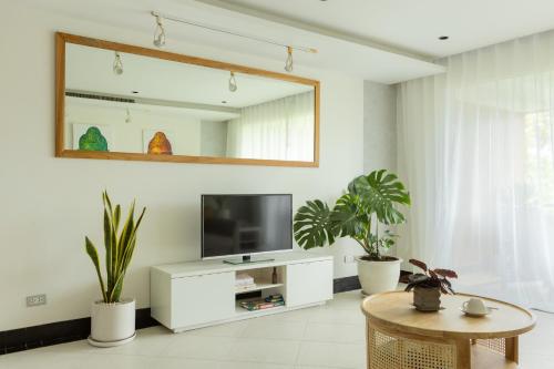a living room with a tv and potted plants at Kata Views by SJ & MJ in Kata Beach