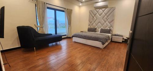 a bedroom with a bed and a chair and a window at Haven Lodge - 7BR Luxury Vacation Home with Mountain View in Islamabad
