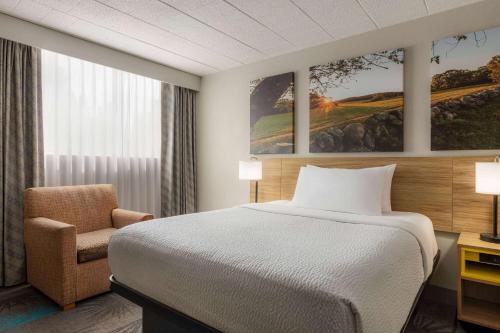a hotel room with a bed and a chair at Days Hotel by Wyndham Allentown Airport / Lehigh Valley in Allentown