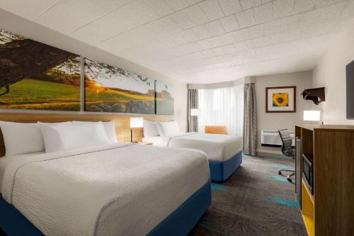 a hotel room with two beds and a desk at Days Hotel by Wyndham Allentown Airport / Lehigh Valley in Allentown