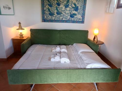 a green bed with two pairs of towels on it at CAPO CODA CAVALLO VILLA SALINEDDA GIARDINO VISTA MARE in Capo Coda Cavallo